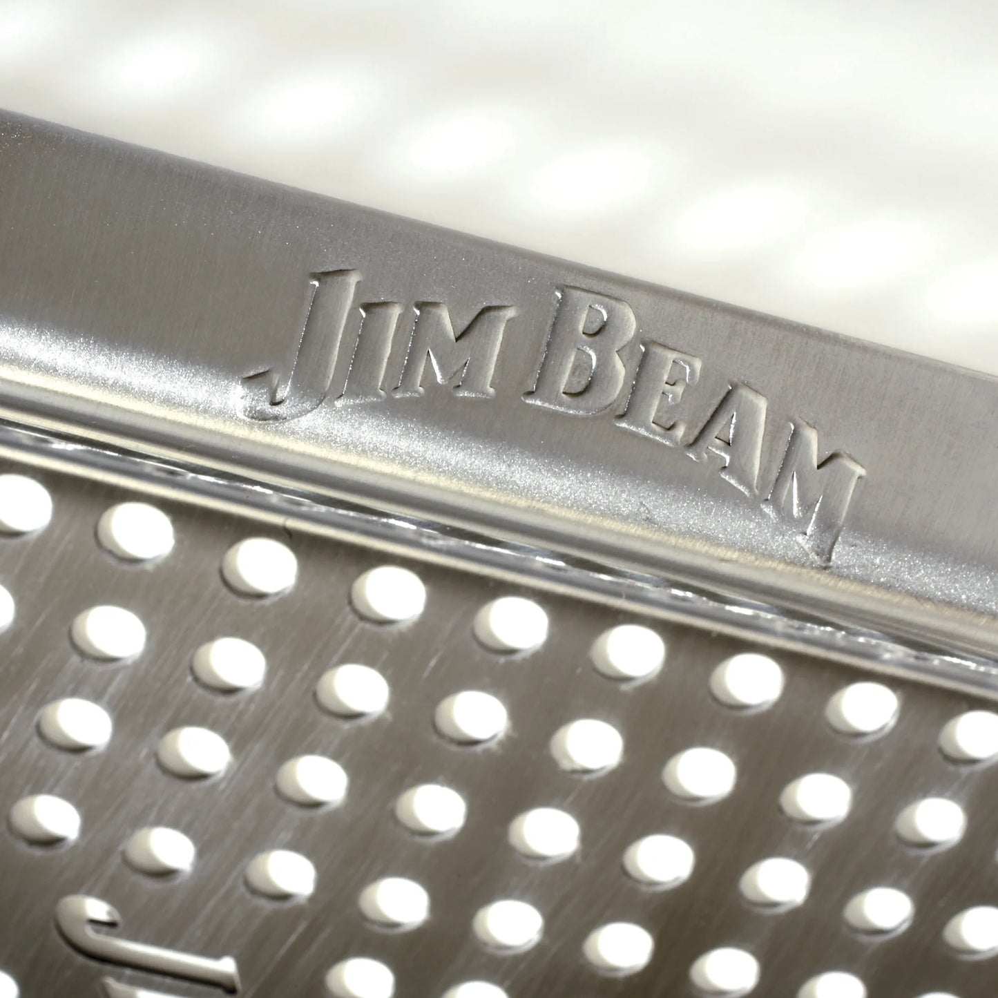 Close-up of a Jim Beam metal grater with the brand name engraved on top. Its brushed steel and even holes pair perfectly with your Jim Beam Stainless Steel Grilling Wok collection.