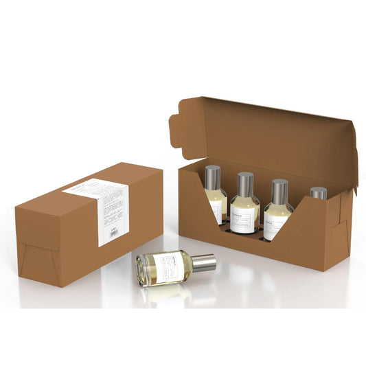 Four small bottles with silver caps from the Emper Discovery Set of 4 Luxury Fragrance Collection are displayed—three in an open brown box, one in front, and another closed box beside them. Ideal for fragrance connoisseurs.