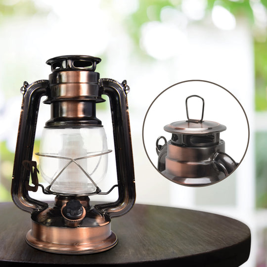 The North Point Vintage LED Lantern with Built-in Dimmer Switch features a copper finish, clear glass enclosure, and metal handle, displayed against a white background.