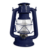 The North Point Vintage LED Lantern by North Point is a classic blue portable lantern with a glass enclosure, metal handle, round base, protective metal frame, and a built-in dimmer switch for adjustable brightness. Shown against a white background.