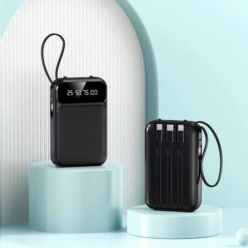 Two North Point 5000mAh black portable power banks with built-in cables, LED display, and flashlight are displayed on light blue circular platforms in a minimal, modern setting. Includes 2-pack.