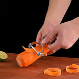 A person peels a carrot on a wooden surface as thin strips of peel gather nearby. A halved lime and the Le Regalo 5 Piece Stainless Steel Colander Set by Le Regalo are in view, all set against a black background.