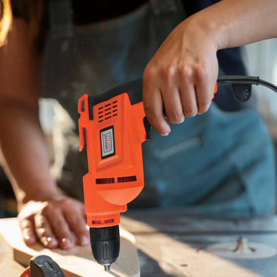 The American Builder Electric Drill, in orange and black with a side grip, is displayed against a white background—a must-have tool for any home improvement project.