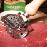 A Jim Beam Stainless Steel Rolling Meat Tenderizer is being used on a raw beef cut, with a Mesquite-labeled box and a bowl of peppercorns in the background.