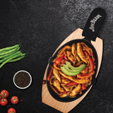 Seasoned chicken strips with sautéed red and yellow bell peppers and avocado slices served in a Jim Beam Cast Iron Skillet Set by Jim Beam, presented on a wooden board with green beans, cherry tomatoes, and peppercorns nearby.