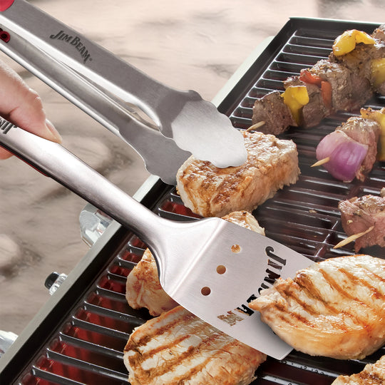 Ideal for grill enthusiasts, the Jim Beam 3 Piece Grill Tool Set includes stainless steel tongs, a slotted spatula, and a grill brush with scraper—each featuring red handle accents.