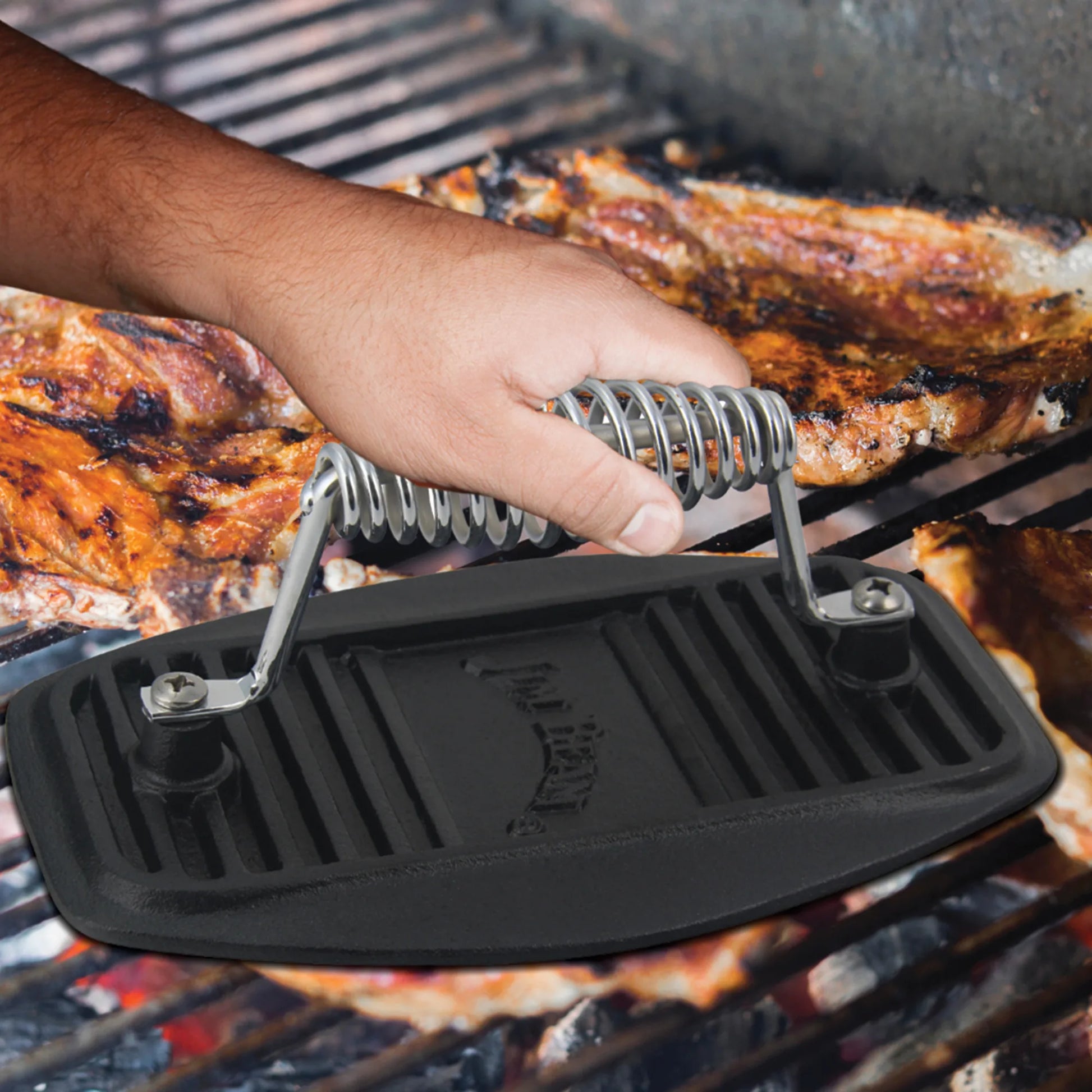 A grilling enthusiast uses the Jim Beam Cast Iron Meat Press with a spiral metal handle to press meat on the barbecue.