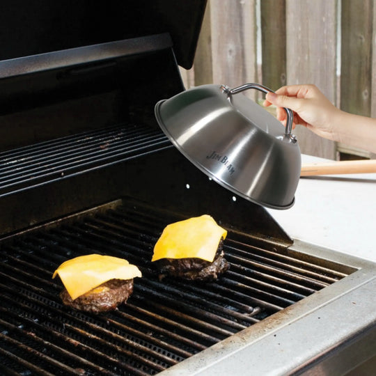 The Jim Beam Stainless Steel 9 Burger Dome features a top handle and branded logo, making it ideal for enhancing your grilling experience and evenly melting cheese on burgers.