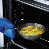 Using a blue oven mitt, someone is placing or removing a baked egg and spinach dish in the Jim Beam Cast Iron 3 Piece Skillet Set, highlighting the versatility of pre-seasoned cookware from Jim Beam.