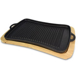 The Jim Beam Cast Iron Grill Pan Set by Jim Beam is a rectangular black pan with dual handles, resting on a light wooden serving tray. Raised ridges make it ideal for stovetop grilling.