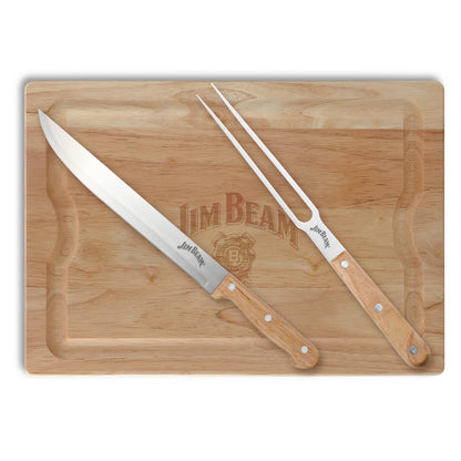 A carving knife and fork set on a wooden cutting board with "Jim Beam" brand have wooden handles and are positioned diagonally across the board.