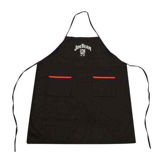 Someone grills outdoors wearing the Jim Beam Classic Grilling Apron, holding a spatula at the barbecue, with greenery in the background.