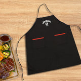 A Jim Beam Classic Grilling Apron in black with two red-trimmed pockets is displayed on a wooden surface, next to a tray holding grilled steak, vegetables, and a cup of sauce.