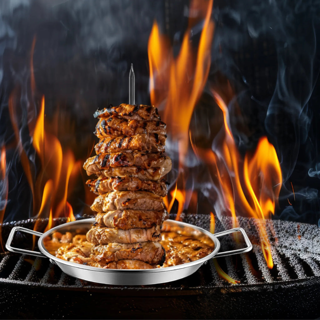 Grilled meat is stacked on a stainless-steel skewer from the North Point 4 Piece Skewer Grill Topper Set, set over a barbecue grill with flames and smoke rising, creating a dramatic cooking atmosphere. Brand: North Point.