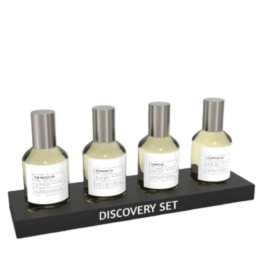 Four Emper Discovery Set bottles from the Luxury Fragrance Collection, each with a silver cap and white label, are arranged on a black DISCOVERY SET stand against a white background—ideal for fragrance enthusiasts.
