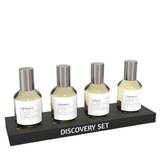 Four small bottles with silver caps from the Emper Discovery Set of 4 Luxury Fragrance Collection are displayed—three in an open brown box, one in front, and another closed box beside them. Ideal for fragrance connoisseurs.