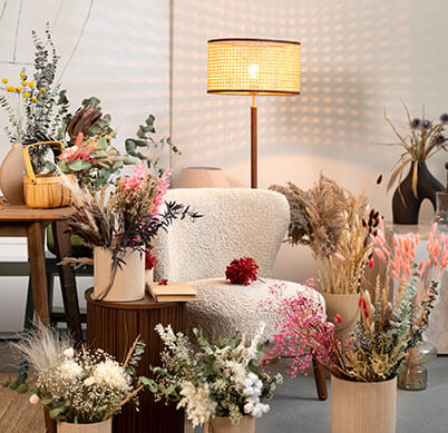 A cozy chair surrounded by an array of colorful dried flowers and a stylish lamp, creating a warm, inviting atmosphere.